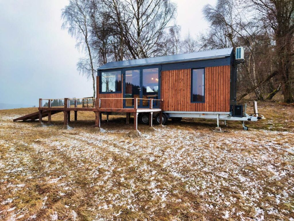 Modulový dům na klíč s dřevěnou fasádou, velkými okny a venkovní terasou.