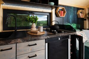 Zahradní domky – interiér moderního Tiny House s dřevěným obložením, posezením a kuchyňským koutem.